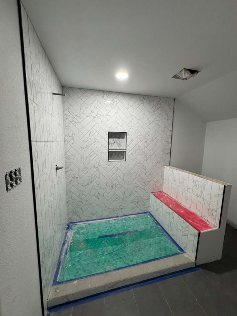 Ducha en construcción con azulejo espina de pez y banco de obra