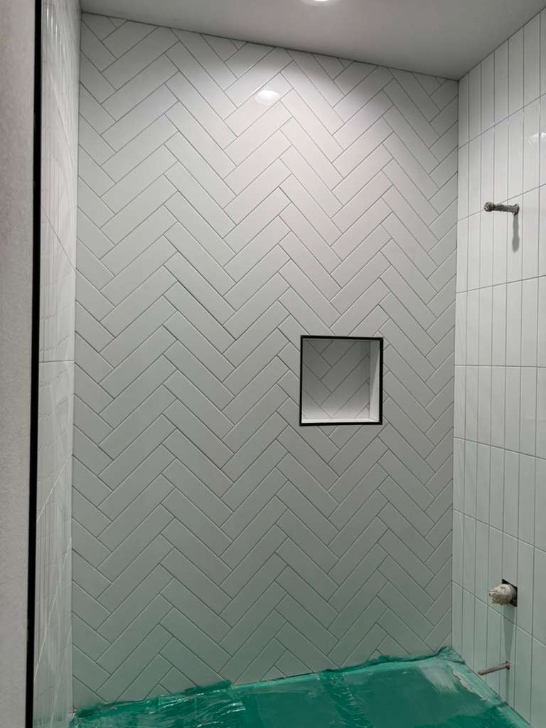 Pared de ducha con azulejo en patrón espina de pez y nicho